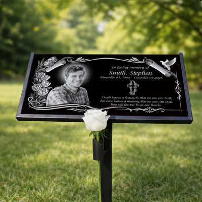 Memorial plaque with a photo of a man, engraved text, and a white rose on a grassy background.