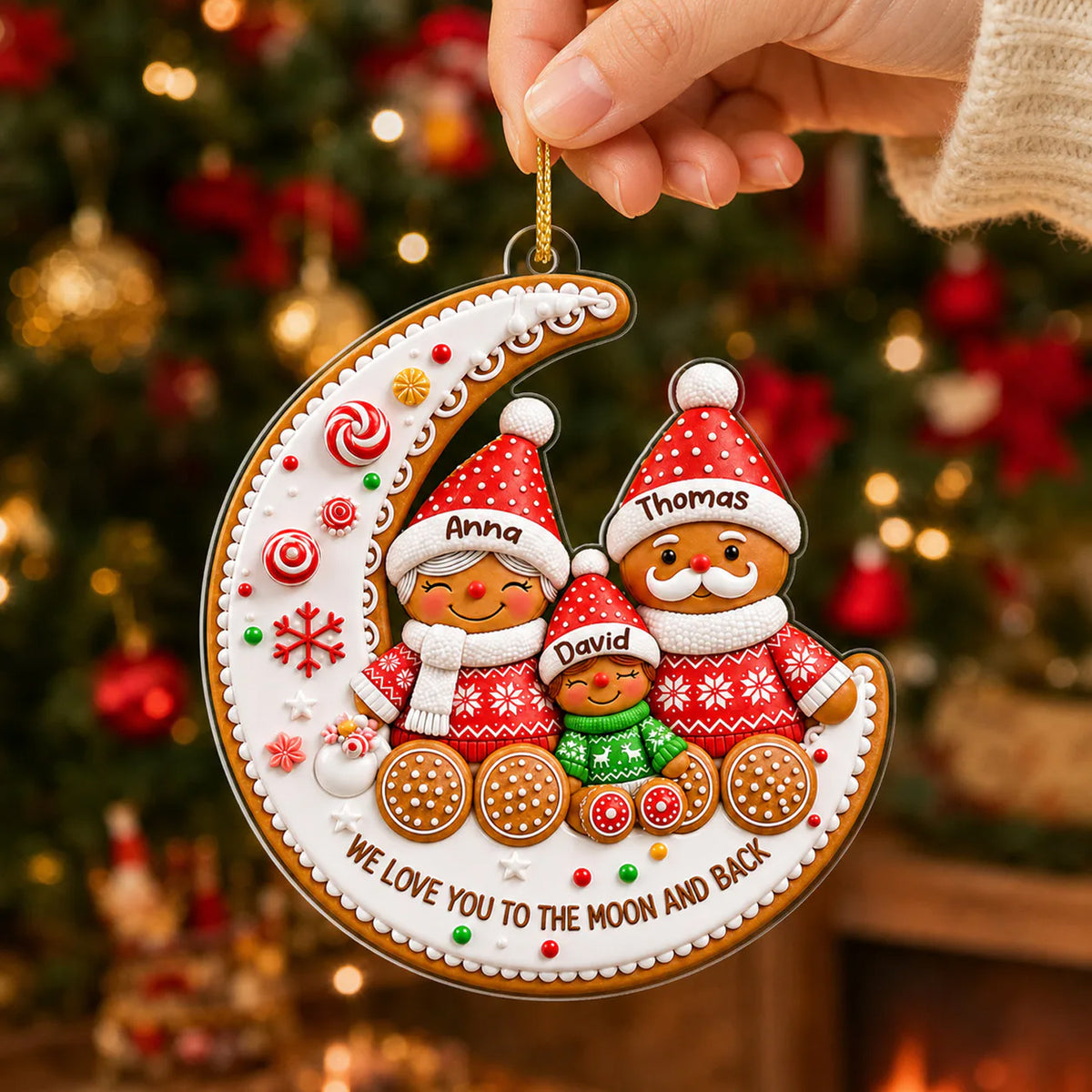 Gingerbread Family Moon Personalize Acrylic Ornament held by a hand near a lit Christmas tree