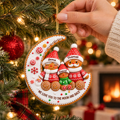 Gingerbread Family Moon Personalize Acrylic Ornament held by hand beside a tree, fireplace and gifts