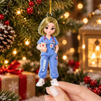 Personalized nurse acrylic ornament held in a hand before a lit tree, red baubles and a gift in view