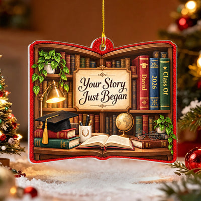 Personalized acrylic library shelf ornament on snowy surface beside a lit Christmas tree and red baubles