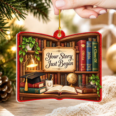 Personalized acrylic library shelf ornament held by a hand, showing a grad cap, books and globe on the shelf