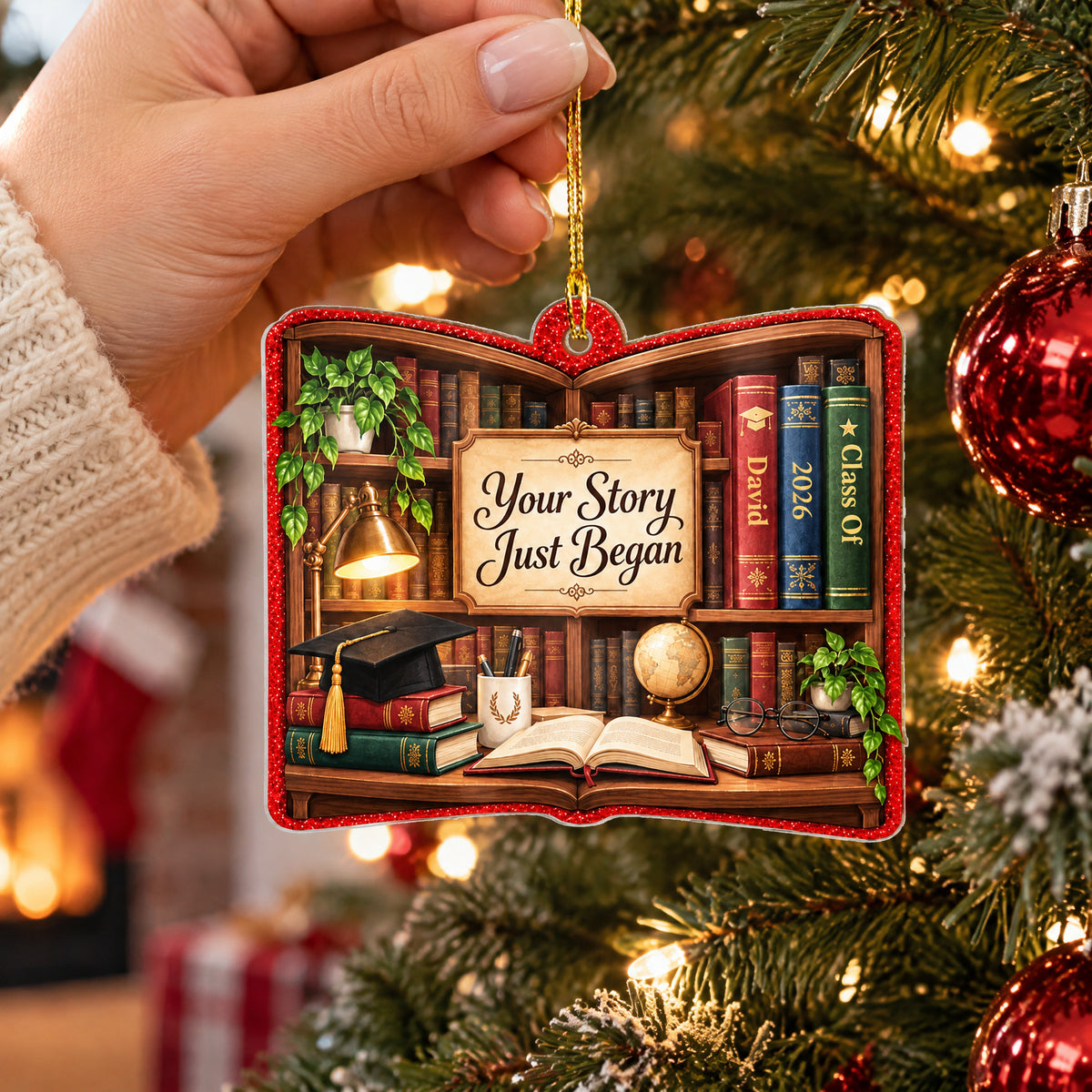 Personalized acrylic library shelf ornament held up near a Christmas tree with red baubles and a cozy knit sleeve