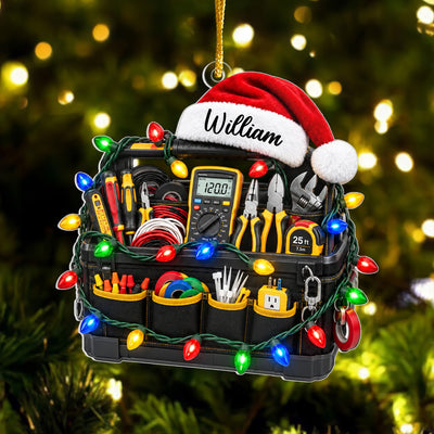 Personalized electrician tool bag acrylic ornament hanging on a tree with blurred warm lights behind