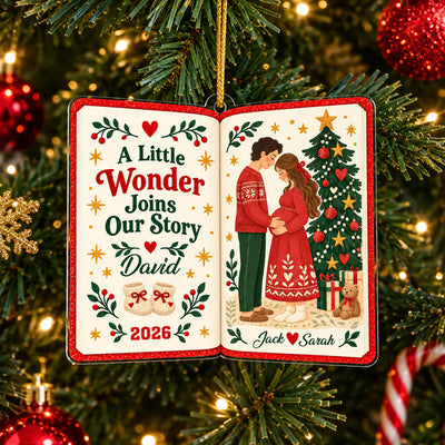 Personalized acrylic book ornament hanging on a pine branch with warm lights and red ornaments