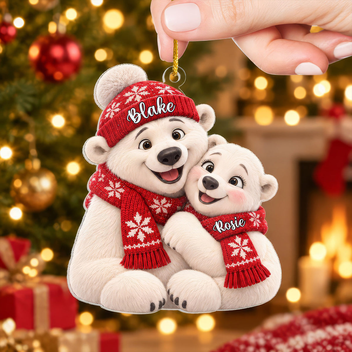 Personalized polar bear couple acrylic ornament held by hand in front of a lit tree, names Blake and Rosie on red scarves