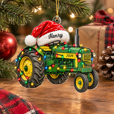 Personalized tractor acrylic ornament near a plaid wrapped gift, pinecone and red bauble on a wooden table