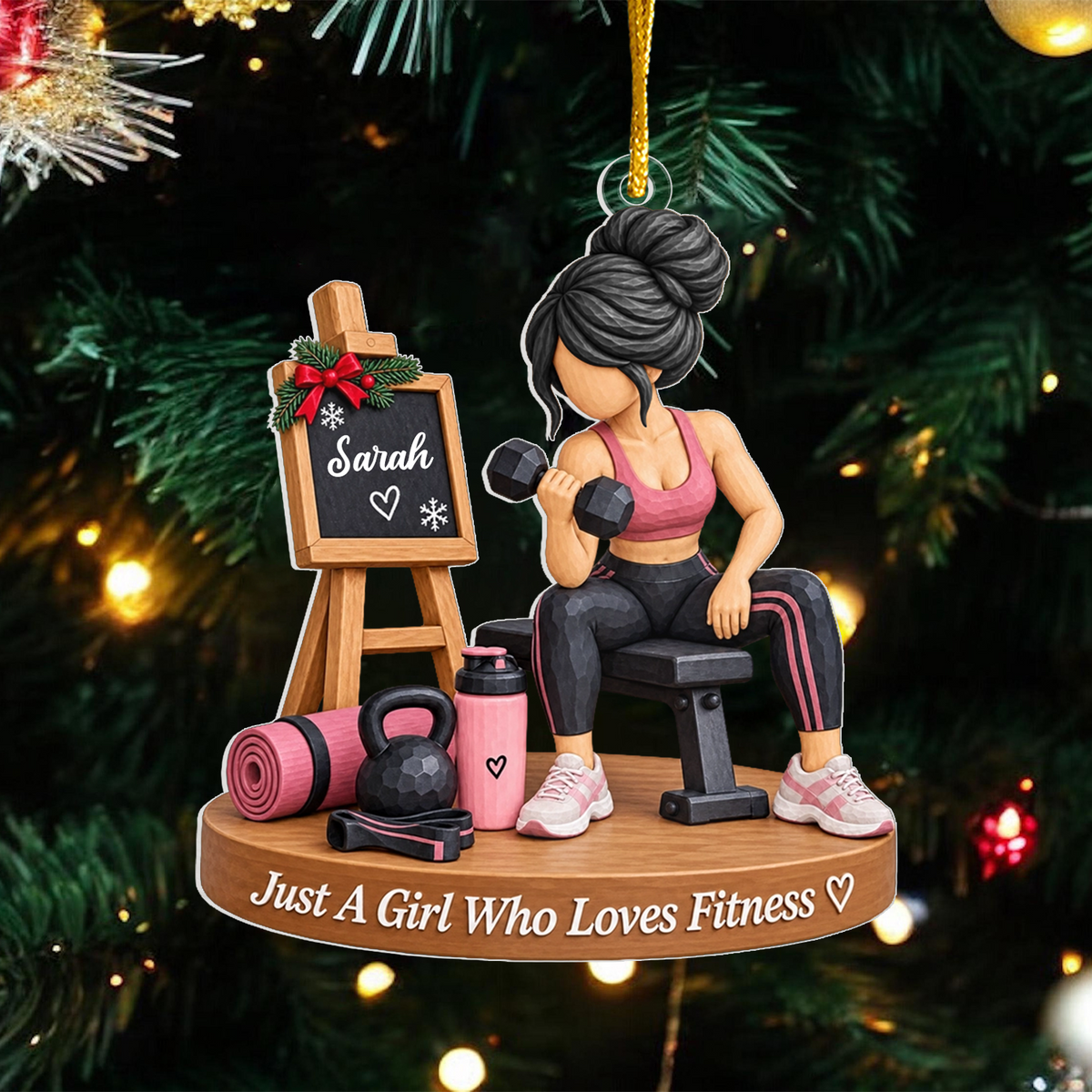 Personalized fitness girl acrylic ornament with dark hair bun and Sarah chalkboard hanging on a green tree