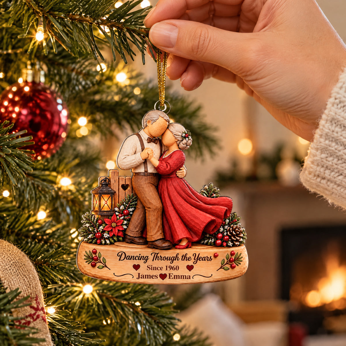 Personalized Acrylic Ornament Dancing Couple held by a hand near a lit tree, red bauble and fireplace behind