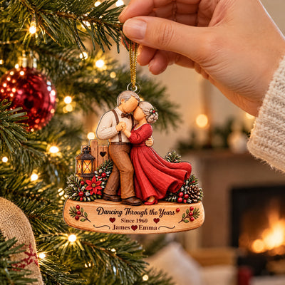 Personalized Acrylic Ornament Dancing Couple held by a hand near a lit tree, red bauble and fireplace behind