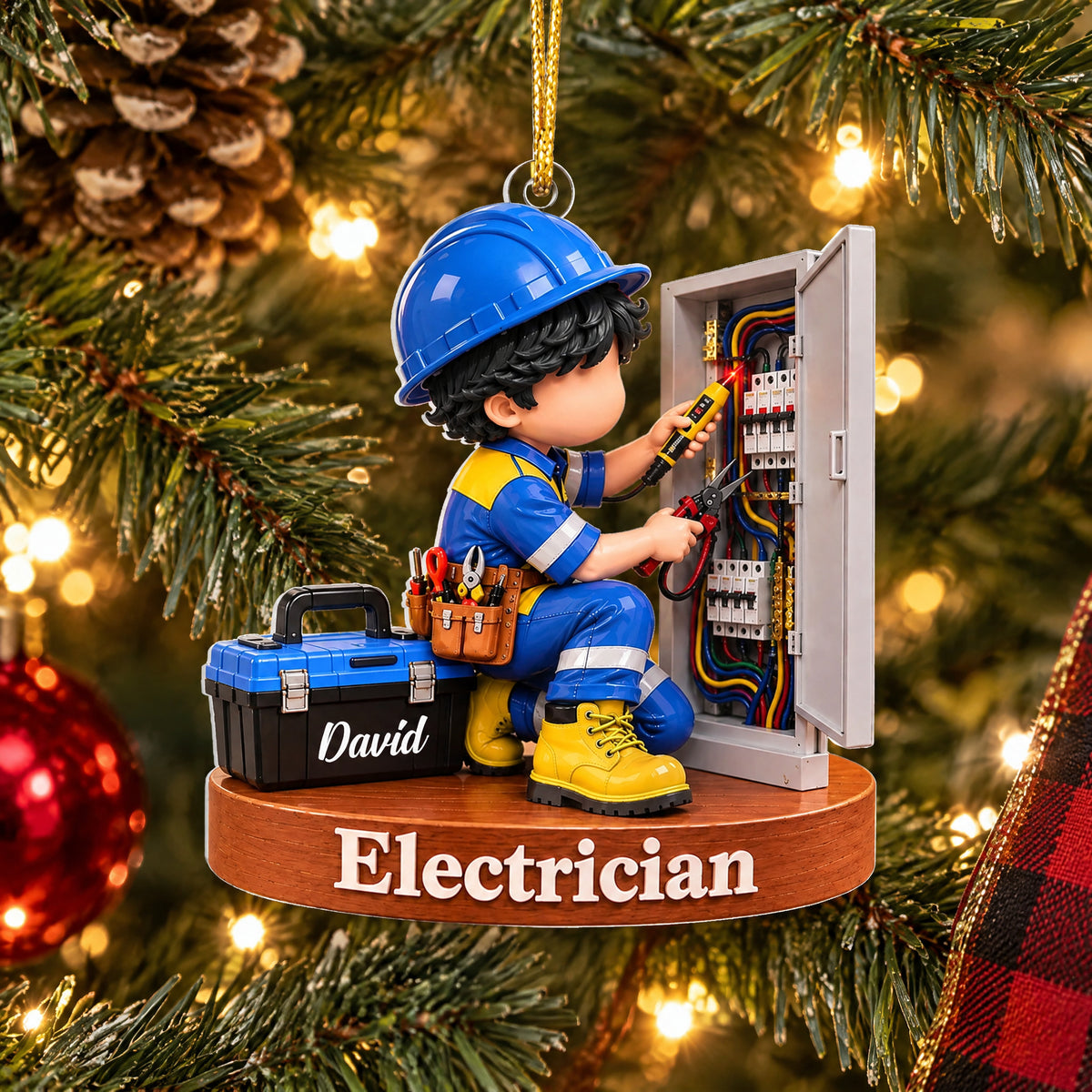 Personalized acrylic electrician Christmas ornament hanging on a tree beside a red bauble and plaid ribbon