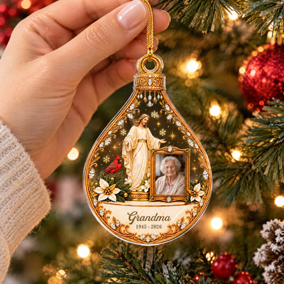 Personalized Christian memorial acrylic ornament held by hand in front of tree lights, showing Grandma name and dates