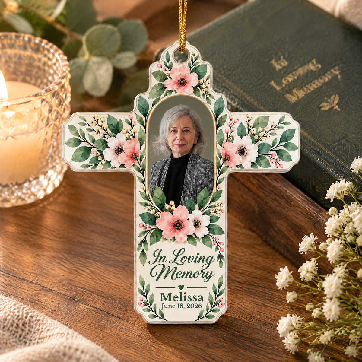 Personalized Floral Cross Acrylic Ornament on a wooden table beside a candle, dark book and white flowers