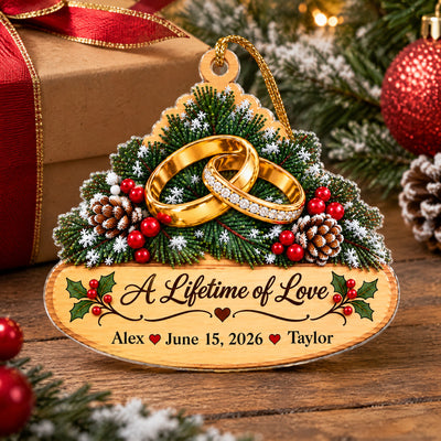 Personalized golden rings acrylic ornament standing on a wooden surface next to a wrapped gift with red ribbon