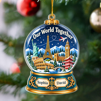 Personalized acrylic snow globe ornament with names Sophia and David hanging on a blurred Christmas tree