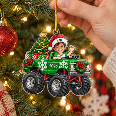 Christmas Monster Truck Personalized Acrylic Ornament hanging on a lit tree with a waving boy in a Santa hat