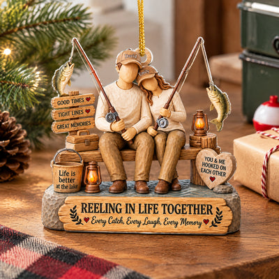 Personalized Acrylic Ornament Reeling In Life Together standing on a wooden table with a gift and plaid cloth