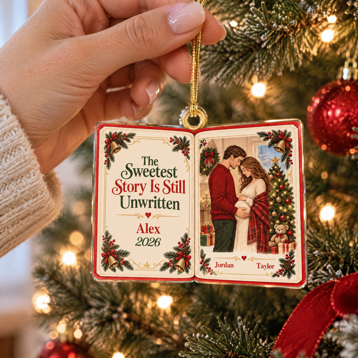 Personalized acrylic book ornament held by a hand by its gold cord in front of a lit Christmas tree