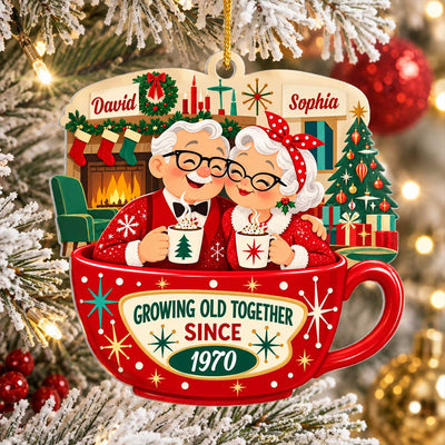 Personalized Christmas acrylic ornament with elderly couple in a red cocoa cup, hanging on a frosted tree beside red baubles