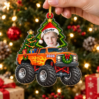 Monster Truck Personalized Acrylic Ornament held by a hand in front of a tree and wrapped gifts
