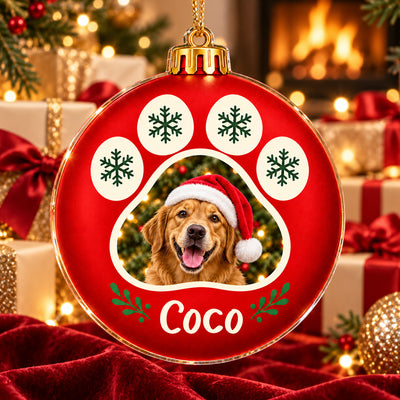 Personalized Acrylic Ornament Paw Print Frame with wrapped gifts, gold ribbons and a fireplace glowing behind it