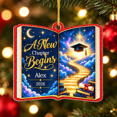 Personalized acrylic celestial graduation ornament hanging on a decorated Christmas tree with warm lights