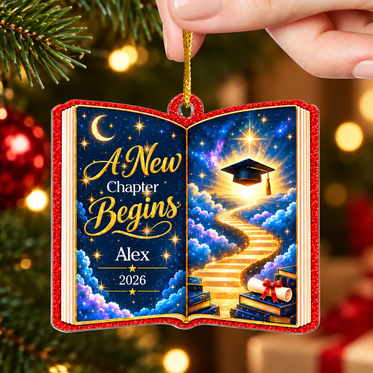 Personalized acrylic celestial graduation ornament held by a hand near tree branches and red baubles