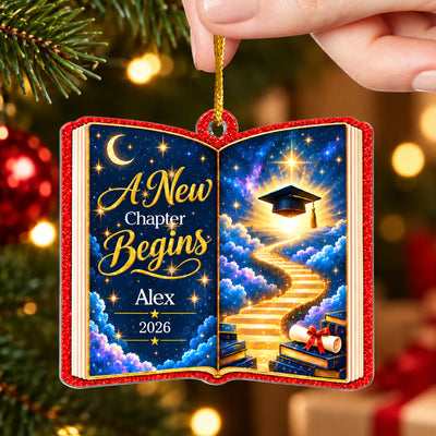 Personalized acrylic celestial graduation ornament hanging on a decorated Christmas tree with warm lights