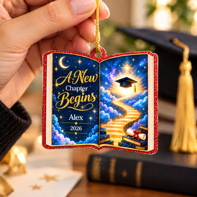 Personalized acrylic celestial graduation ornament held up by a hand with a graduation cap tassel behind