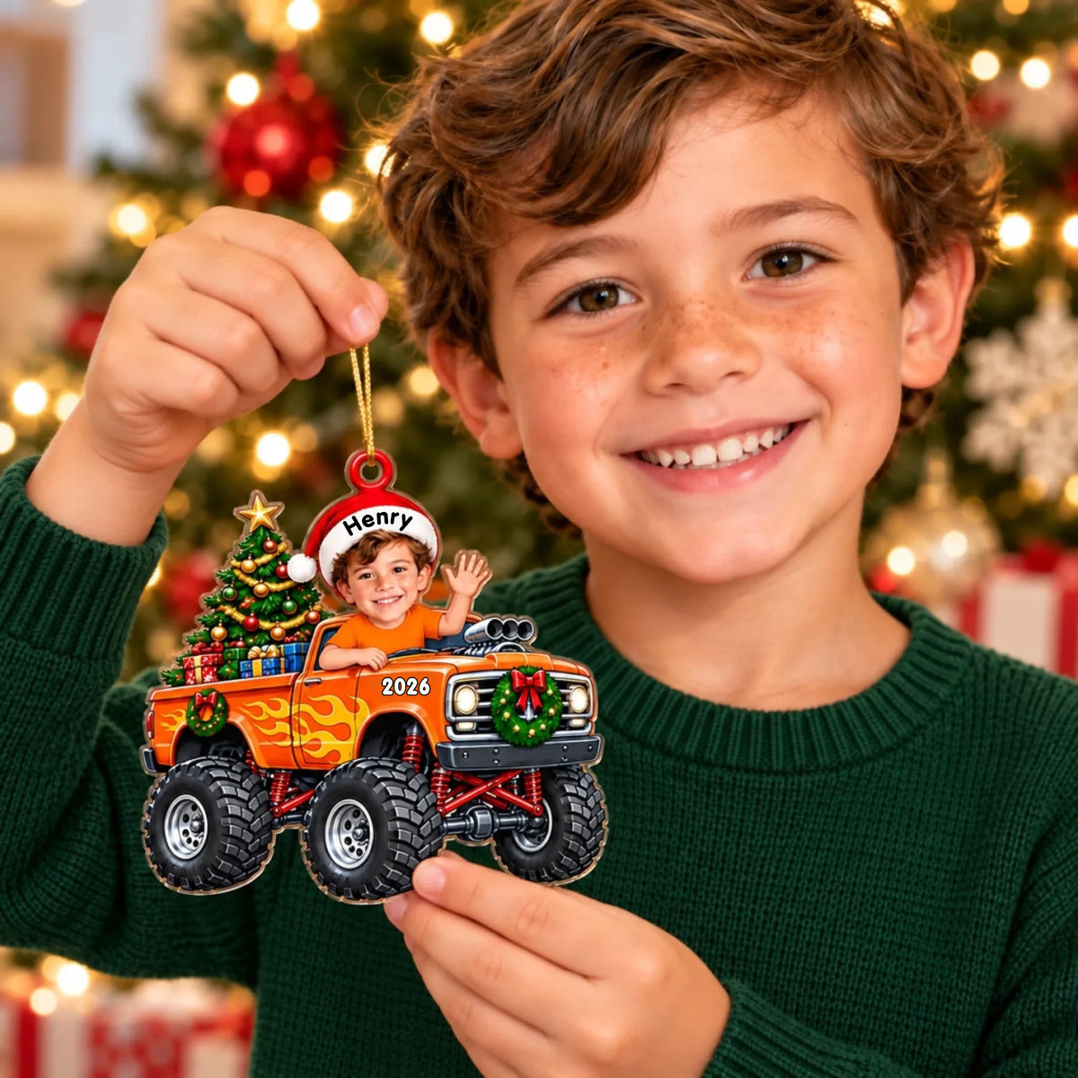 Personalized orange monster truck acrylic ornament held by a smiling boy in a green sweater