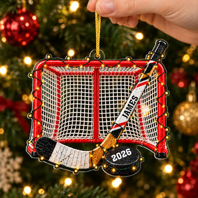 Personalized Acrylic Hockey Ornament held by hand in front of a lit tree with red and gold baubles
