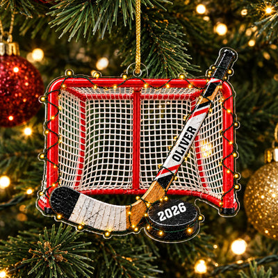 Personalized Acrylic Hockey Ornament hanging on a pine tree with string lights and a gold bauble nearby
