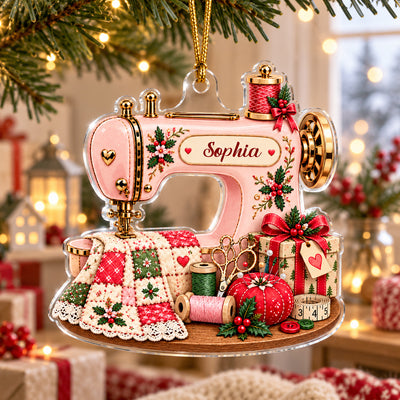 Personalized Sewing Machine Acrylic Ornament hanging on a pine branch with warm string lights behind it