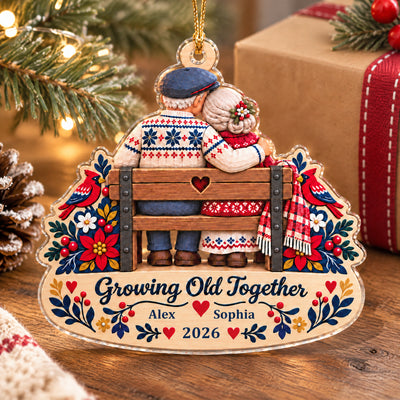 Growing Old Together Personalized Acrylic Ornament standing on a wooden table by a wrapped gift and pinecone