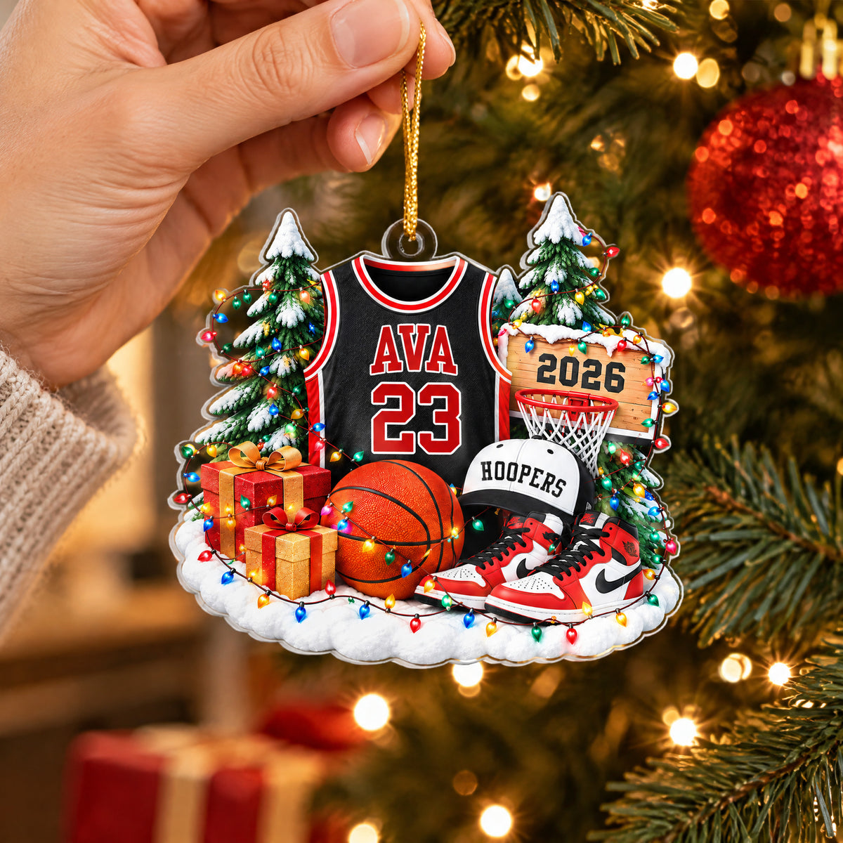 Personalized Basketball Acrylic Ornament held by a hand in front of a tree with red baubles and warm lights