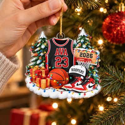 Personalized Basketball Acrylic Ornament held by a hand in front of a tree with red baubles and warm lights