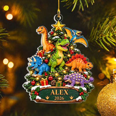 Personalized acrylic dinosaur ornament reading Alex 2026 hanging by a gold cord near a gold bauble