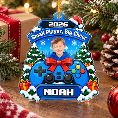 Personalized acrylic gamer ornament standing on a wooden surface near a gift box, pinecone and red bauble