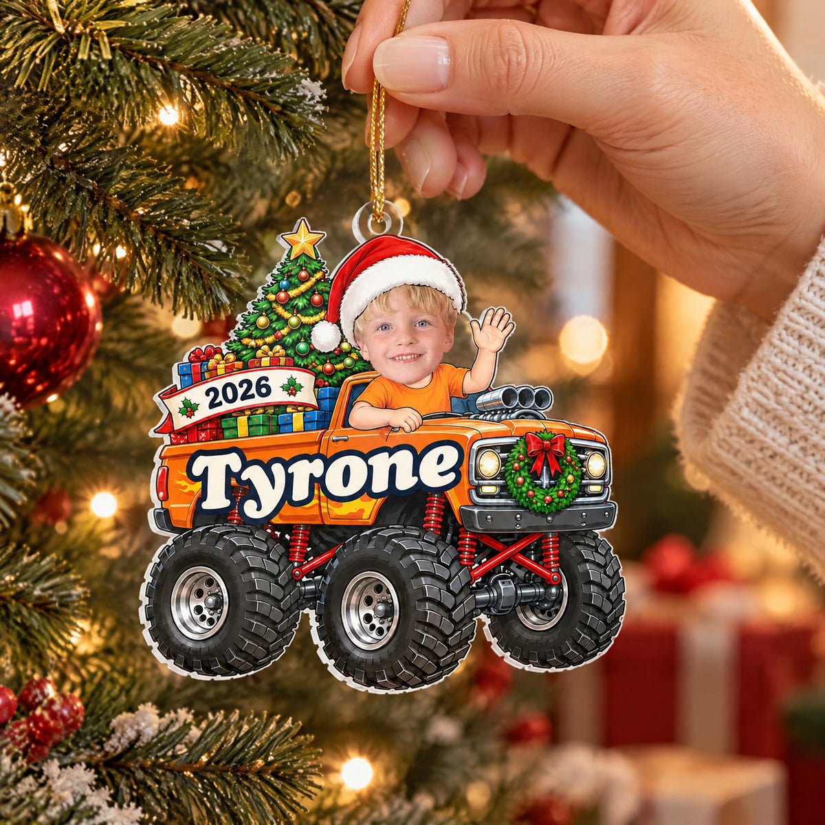Personalized monster truck acrylic ornament, orange truck held by its gold cord on a Christmas tree branch