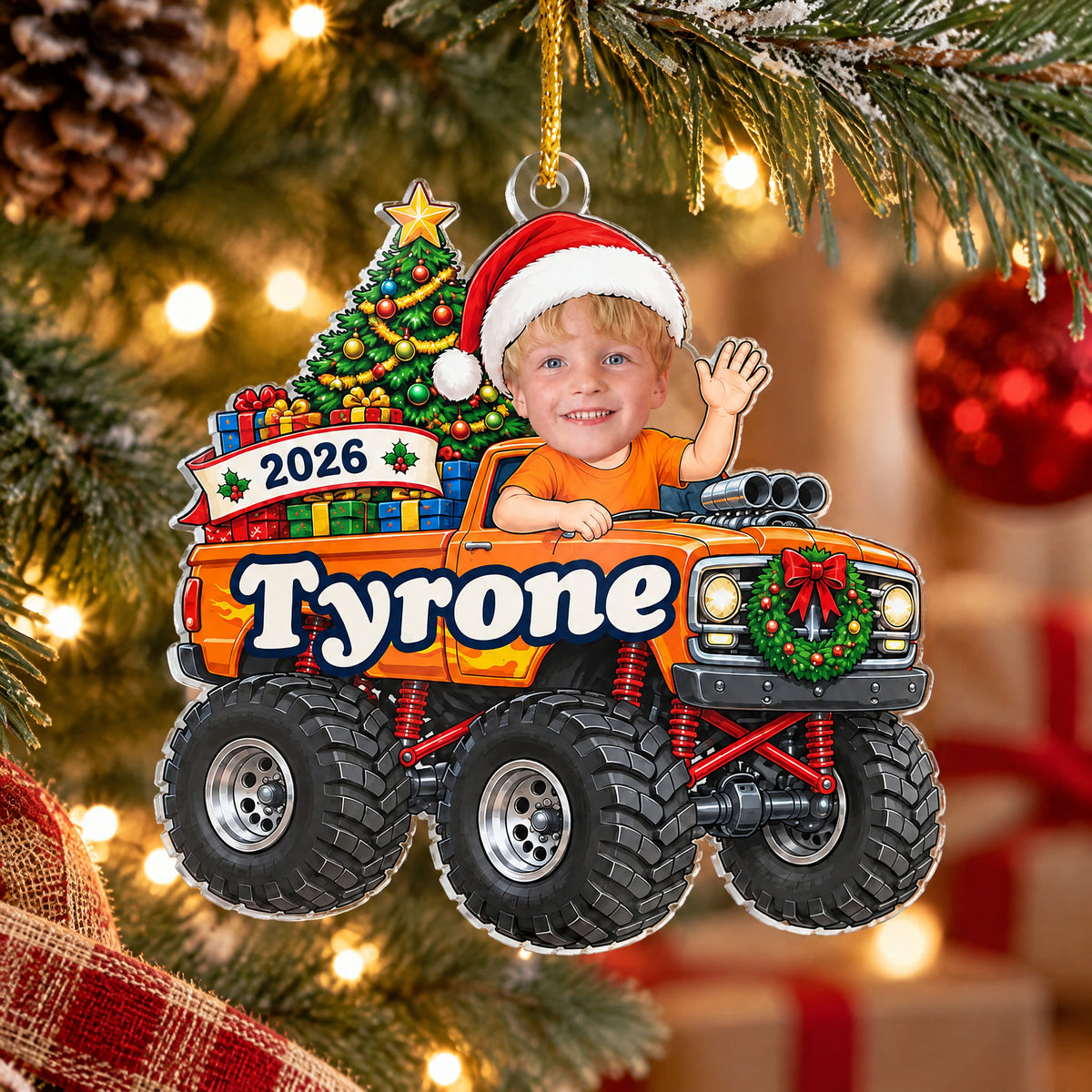 Personalized monster truck acrylic ornament, orange truck hanging on a tree with red baubles and gifts behind