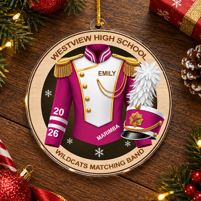 Personalized marching band acrylic ornament in pink lying on a wooden table with pine branches, pinecone and gift