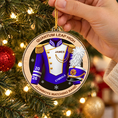 Personalized marching band acrylic ornament in purple held up by a hand in a cream sleeve in front of tree lights