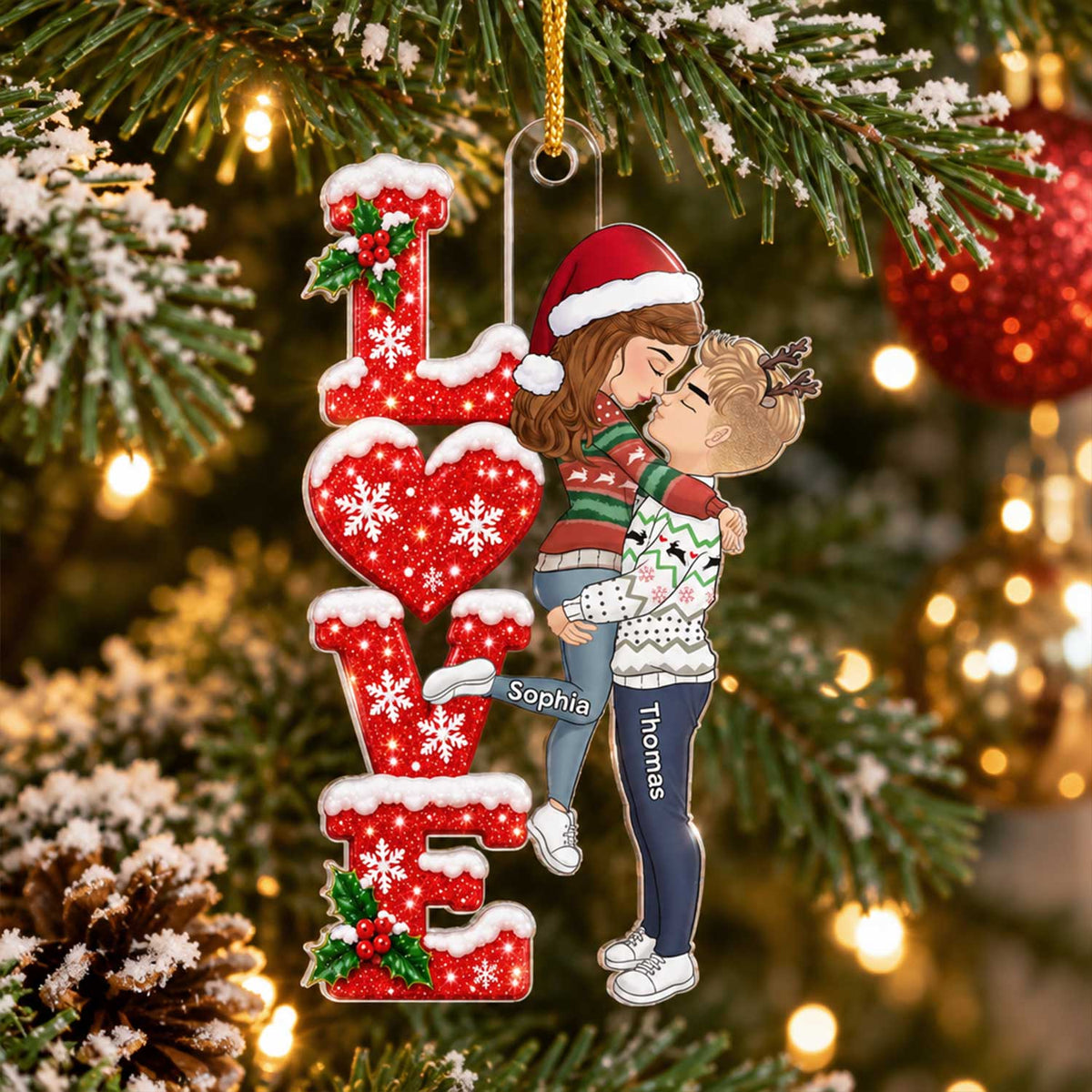 Personalized Acrylic Ornament Kissing Couple hanging on a snowy pine branch with red baubles, names Sophia and Thomas