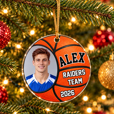 Personalized basketball acrylic ornament on a gold cord, angled view among pine branches and red and gold baubles