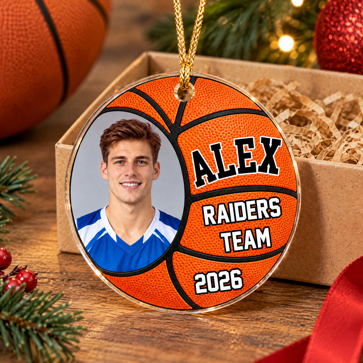 Personalized basketball acrylic ornament resting on a wood table by a kraft gift box with paper shred and red ribbon