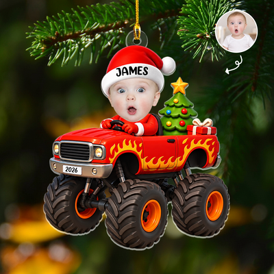 Personalized red monster truck acrylic ornament with surprised baby face, name James, hanging on a pine branch
