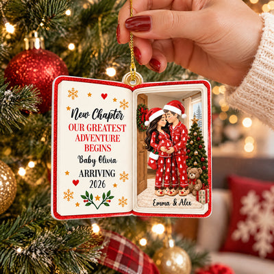 Personalized acrylic book ornament held up near a red plaid ribbon and snowflake pillow, red pajama couple scene