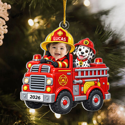Personalized acrylic ornament baby fire engine on a tree with warm lights, name LUCAS on the helmet and 2026 on the plate