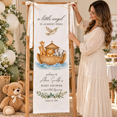 Personalized Baby Shower Backdrop on an easel as a smiling woman in a cream dress adjusts it, with balloons and teddy bear