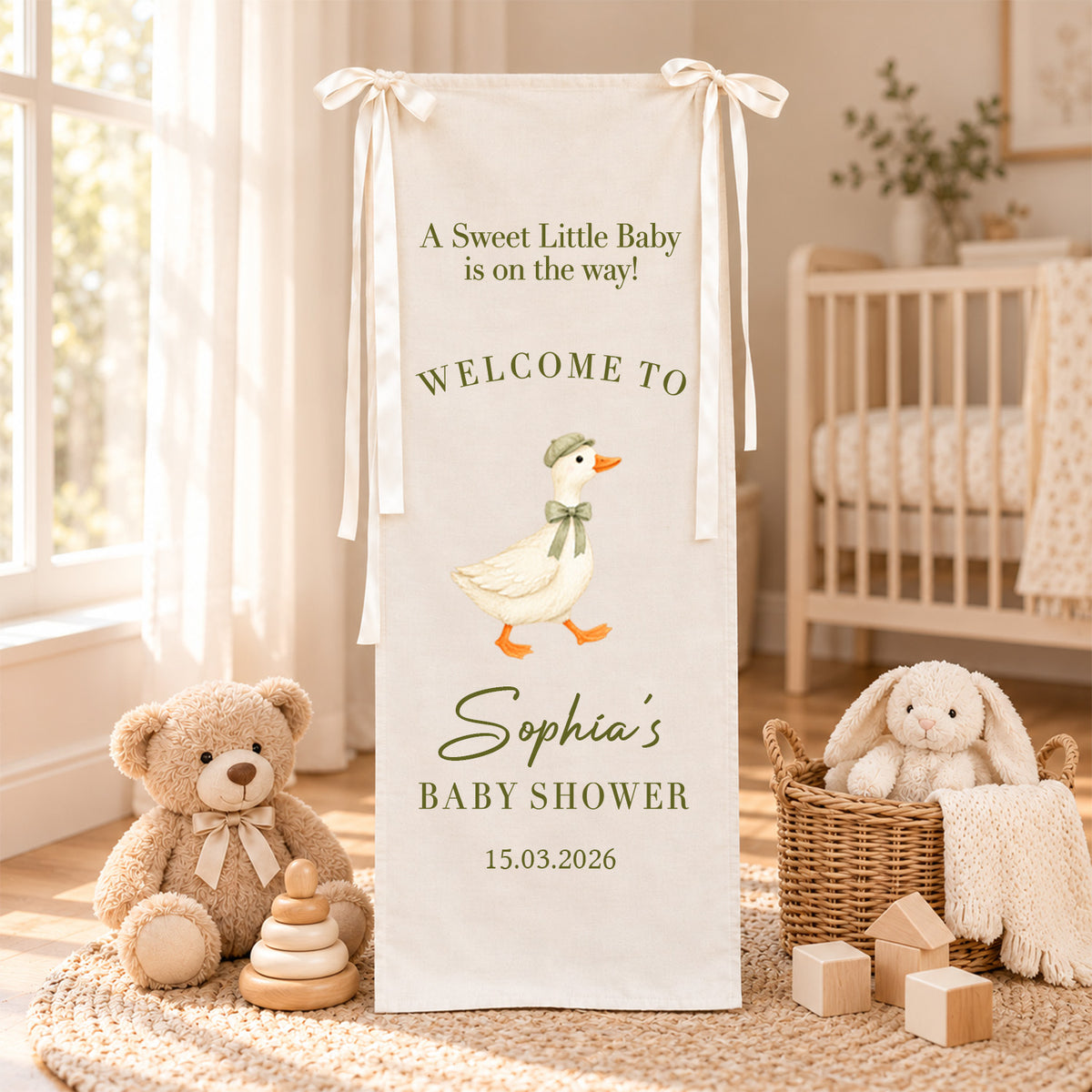 Personalized Baby Shower Welcome Sign Backdrop with goose in green bow in a nursery with crib and teddy bear